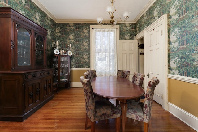 dining space with hardwood / wood-style floors, crown molding, and a notable chandelier