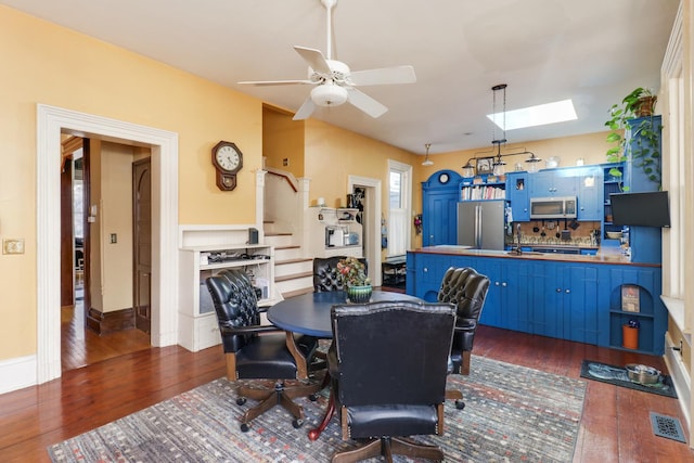 dining area with sink, a skylight, dark hardwood / wood-style floors, and ceiling fan