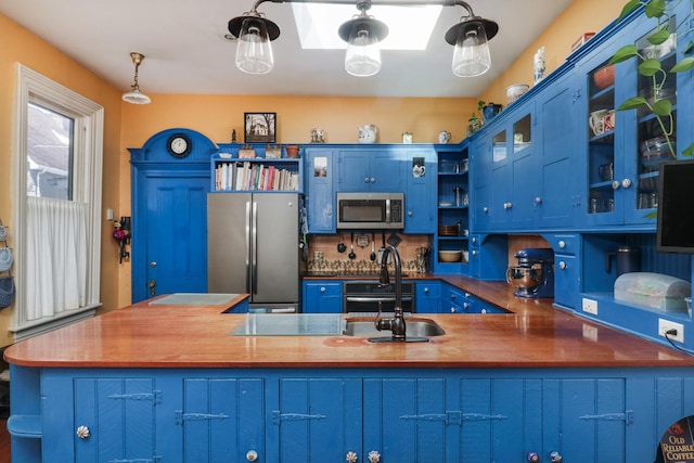 kitchen featuring stainless steel appliances, blue cabinets, and wooden counters