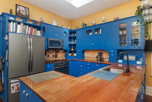 kitchen with butcher block countertops, blue cabinets, black appliances, sink, and kitchen peninsula