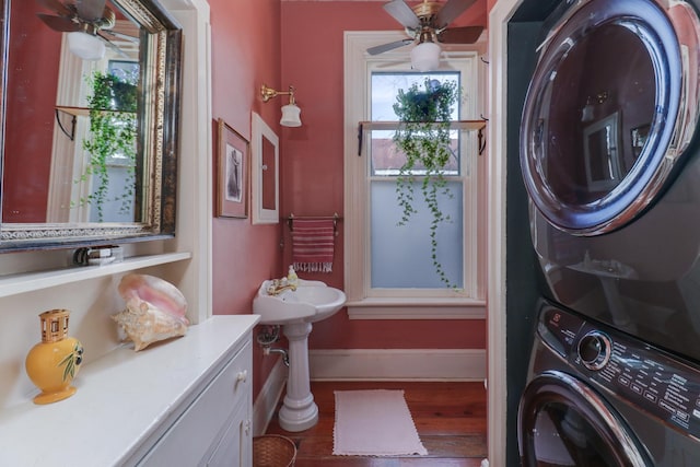 washroom featuring ceiling fan, stacked washer / dryer, and wood-type flooring