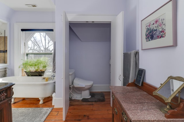 bathroom featuring vanity, toilet, hardwood / wood-style floors, and a tub