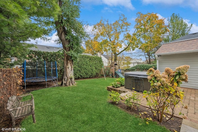 view of yard featuring a trampoline, a hot tub, and a playground