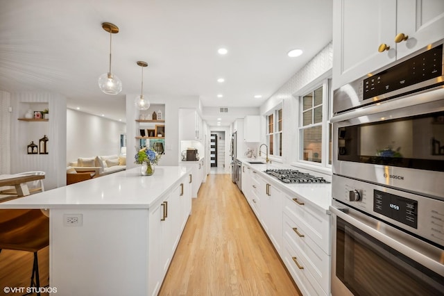 kitchen with stainless steel appliances, a center island, pendant lighting, and white cabinets