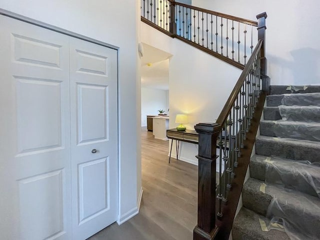 stairs with a towering ceiling and hardwood / wood-style floors