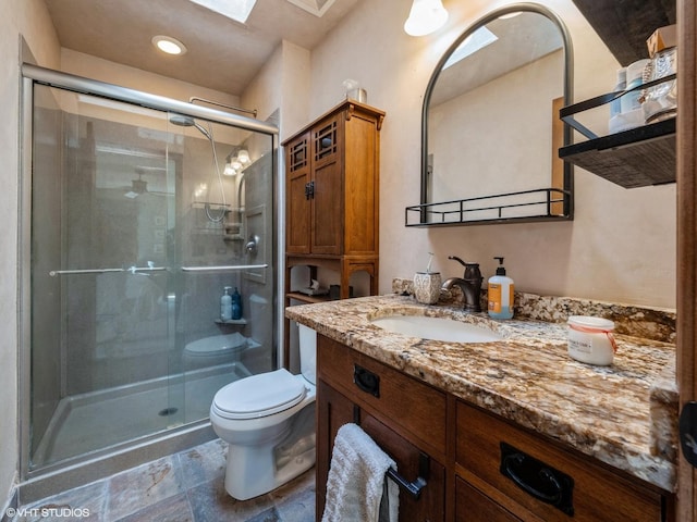 bathroom featuring a skylight, vanity, toilet, and an enclosed shower