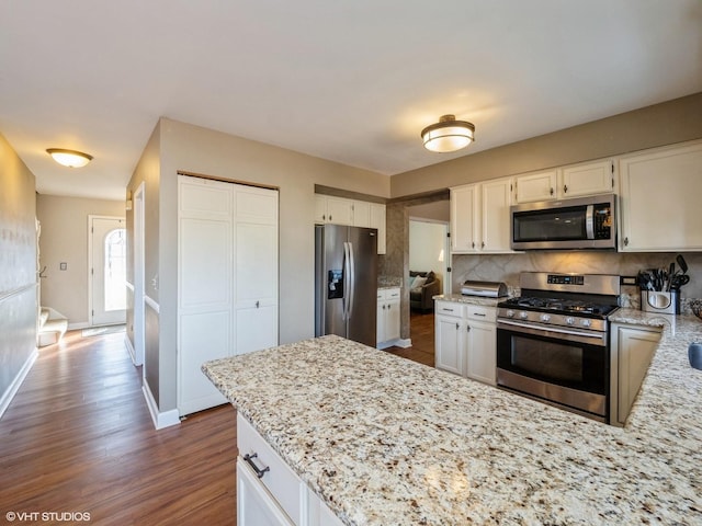 kitchen with light stone counters, appliances with stainless steel finishes, and white cabinets