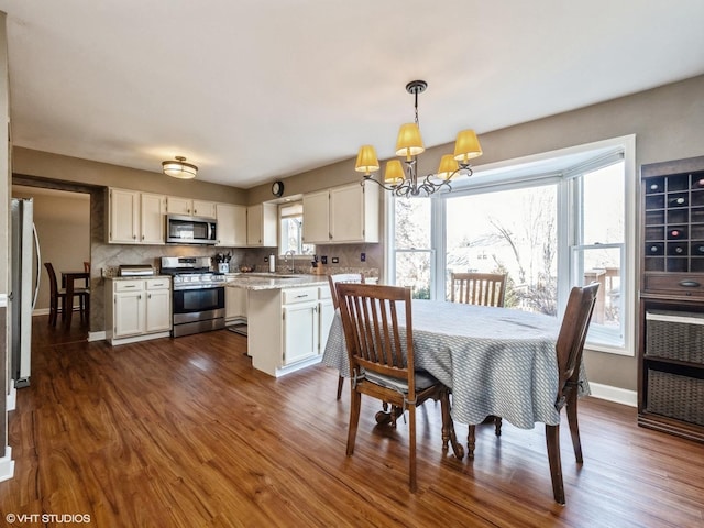 dining space featuring sink, dark wood-type flooring, and a chandelier