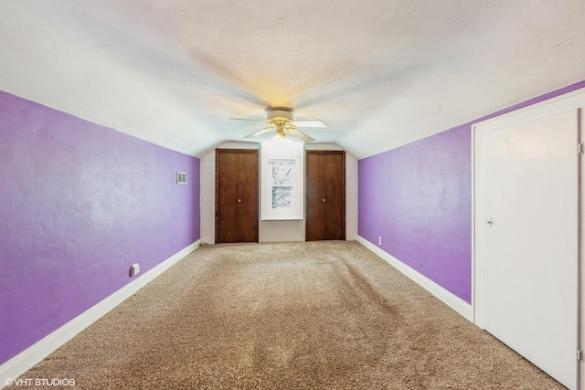 additional living space featuring lofted ceiling, carpet flooring, visible vents, a ceiling fan, and baseboards