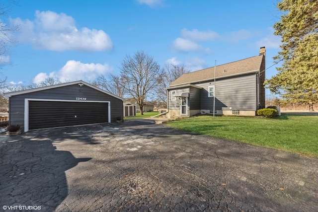 exterior space with a garage, an outbuilding, a lawn, and a chimney