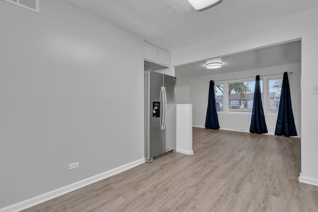 unfurnished room with a textured ceiling and light hardwood / wood-style floors