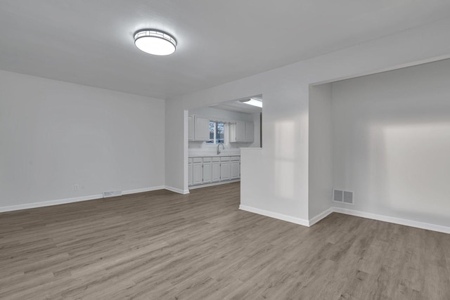 unfurnished living room featuring sink and light hardwood / wood-style flooring