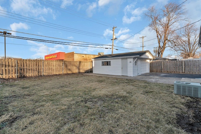 view of yard featuring a garage, an outbuilding, and central AC