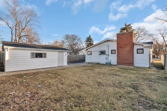 back of house featuring a yard, an outdoor structure, and central air condition unit