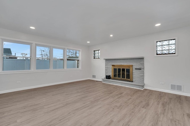 unfurnished living room with a stone fireplace and light hardwood / wood-style floors