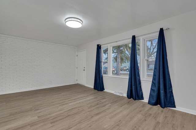 empty room featuring light hardwood / wood-style floors and brick wall