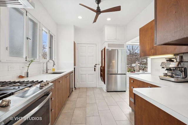 kitchen with decorative backsplash, brown cabinets, stainless steel appliances, light countertops, and a sink