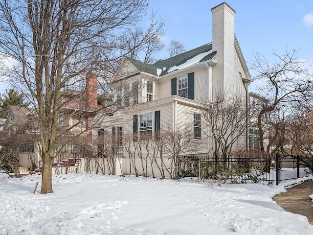 snow covered property with fence and a chimney