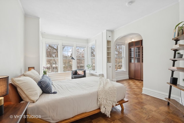 bedroom featuring arched walkways, ornamental molding, wood finished floors, and baseboards