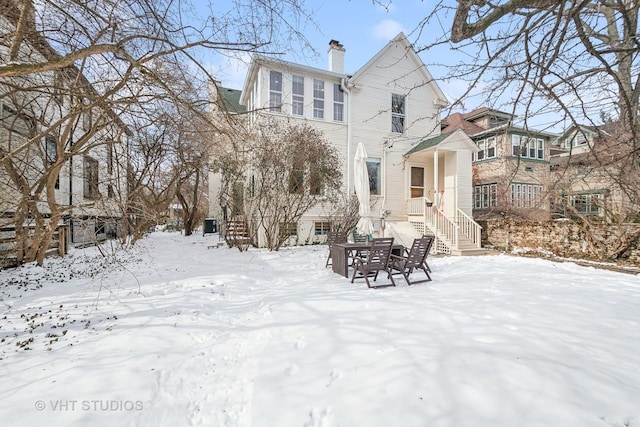 snow covered property featuring a chimney