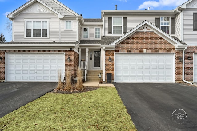 view of property with driveway, brick siding, a front lawn, and an attached garage