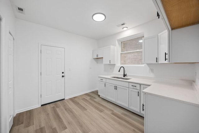 kitchen featuring sink, light hardwood / wood-style flooring, and white cabinets