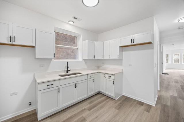 kitchen with sink, white cabinets, and light wood-type flooring