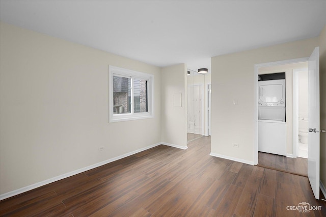 spare room with stacked washer and clothes dryer and dark hardwood / wood-style flooring