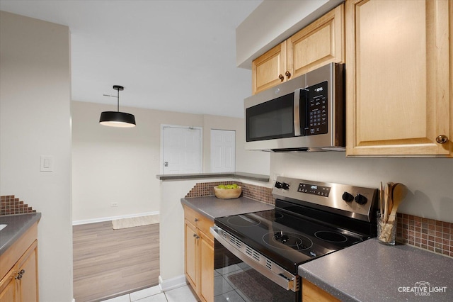 kitchen featuring decorative backsplash, appliances with stainless steel finishes, light brown cabinetry, and hanging light fixtures