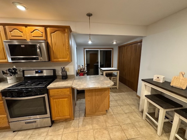 kitchen featuring appliances with stainless steel finishes, decorative light fixtures, and light tile patterned floors