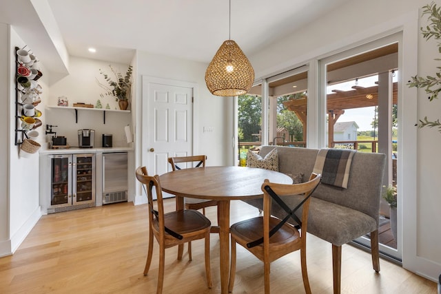 dining area with wine cooler, bar, and light wood-type flooring