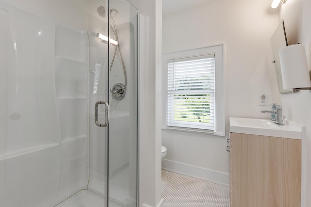 bathroom with a shower with door, vanity, tile patterned flooring, and toilet