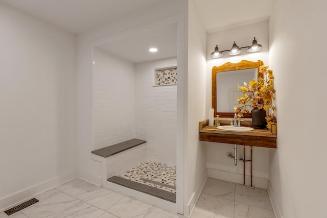 bathroom featuring a tile shower and sink