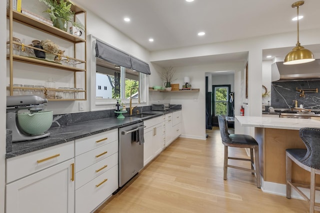 kitchen featuring sink, a breakfast bar area, white cabinetry, stainless steel dishwasher, and dark stone counters