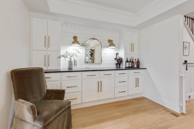 bar featuring white cabinetry, a tray ceiling, light hardwood / wood-style flooring, and crown molding