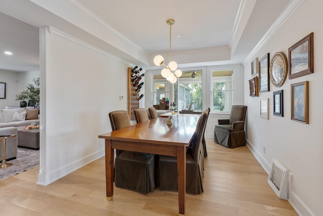 dining room with crown molding, light hardwood / wood-style floors, and a raised ceiling