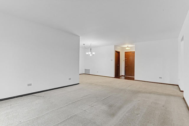 empty room featuring light colored carpet and a chandelier