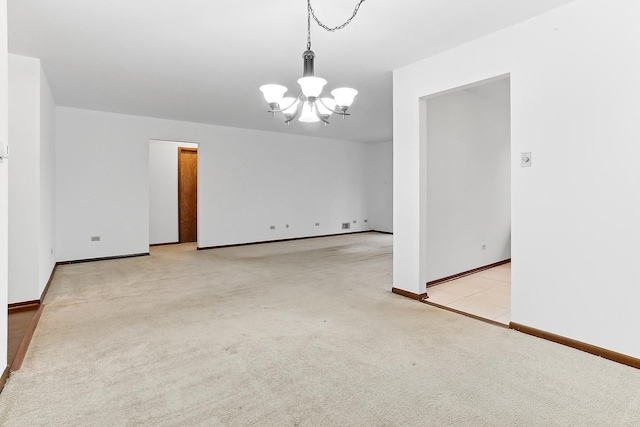 carpeted empty room with an inviting chandelier