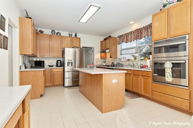 kitchen featuring tasteful backsplash, stainless steel appliances, sink, and a kitchen island