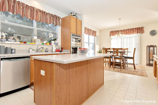 kitchen featuring stainless steel appliances, hanging light fixtures, a kitchen island, and light tile patterned floors