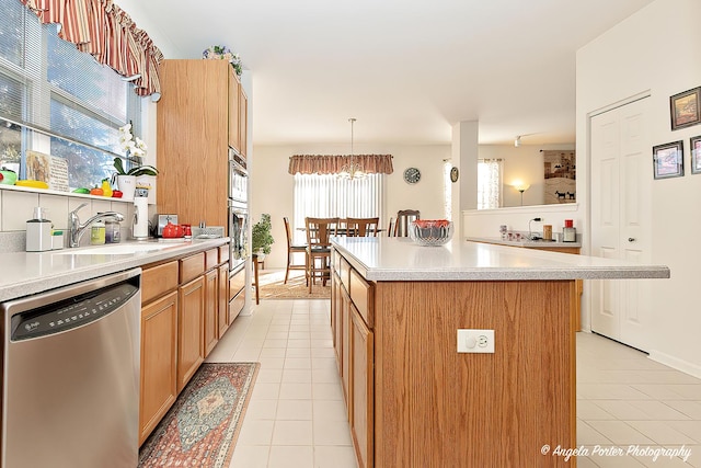 kitchen featuring sink, light tile patterned floors, dishwasher, hanging light fixtures, and a center island