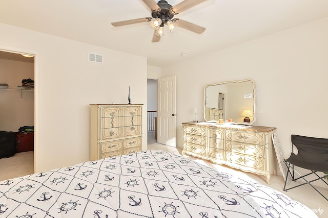 carpeted bedroom with a spacious closet, ceiling fan, and a closet