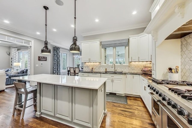 kitchen with pendant lighting, double oven range, sink, and white cabinets