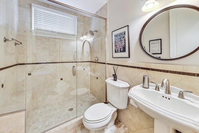 bathroom featuring a shower with door, sink, tile walls, and toilet