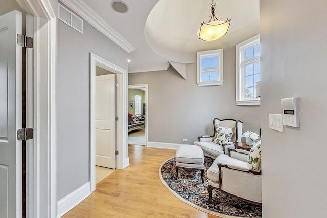 living area with ornamental molding and light hardwood / wood-style flooring