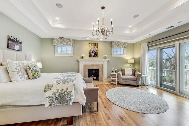 bedroom featuring a raised ceiling, wood-type flooring, ornamental molding, and access to outside