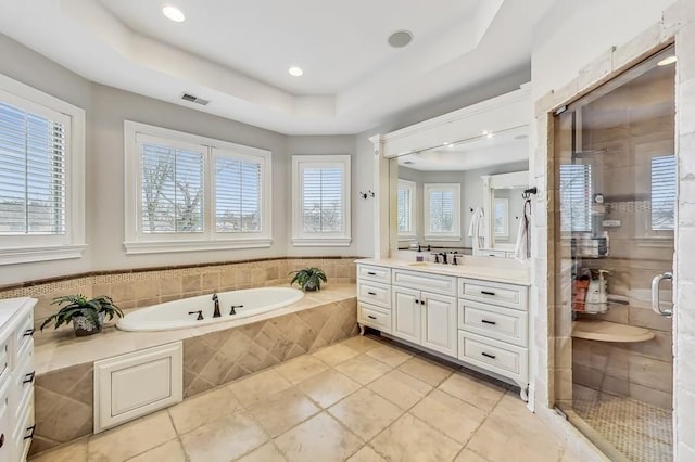 bathroom featuring a raised ceiling, vanity, independent shower and bath, and tile patterned floors