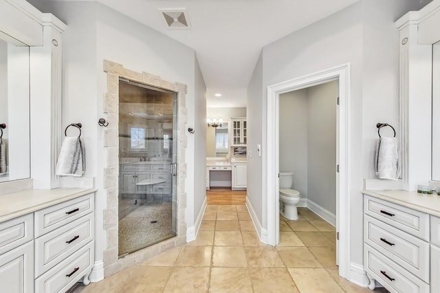 bathroom featuring a shower with door, vanity, tile patterned flooring, and toilet