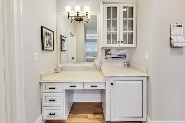 bar with white cabinetry, an inviting chandelier, and light hardwood / wood-style floors