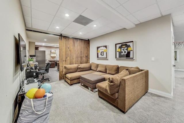 living room featuring light colored carpet, a barn door, and a drop ceiling